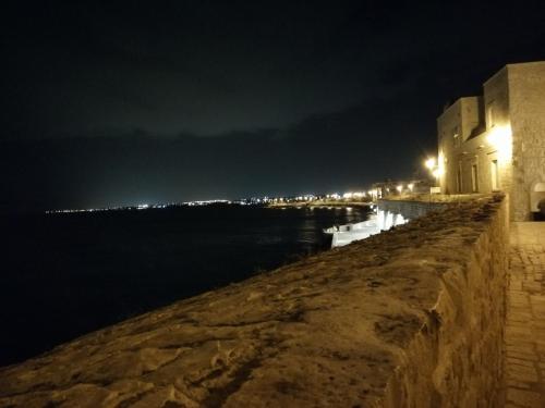 a stone wall next to the water at night at B&B VISTAZZURRA - Casa Saldarelli in Giovinazzo
