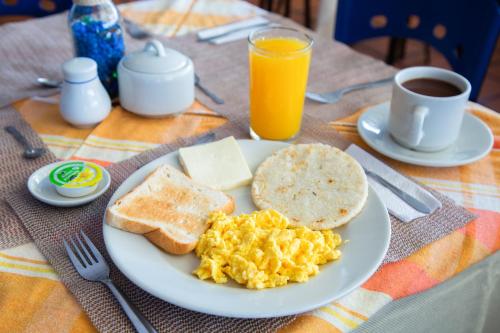 a breakfast plate of eggs and toast and a cup of orange juice at Ayenda 1133 Casa Polty in Manizales
