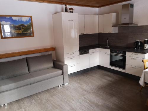 eine Küche mit weißen Schränken und einem grauen Sofa in der Unterkunft Ferienwohnung Peintnerhof in Innervillgraten