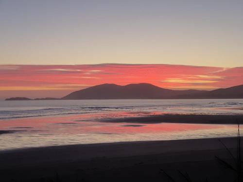 a sunset over a beach with mountains in the background at Skellig Port Accomodation - 2 Bed Apartment in Portmagee