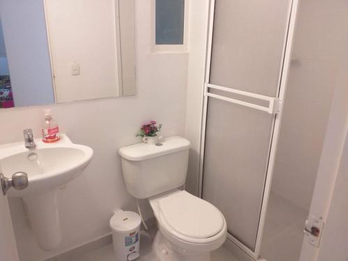 a white bathroom with a toilet and a sink at Apartamento con piscina in Montería