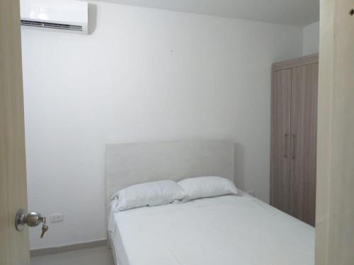 a bedroom with a white bed with a white pillow at Apartamento con piscina in Montería