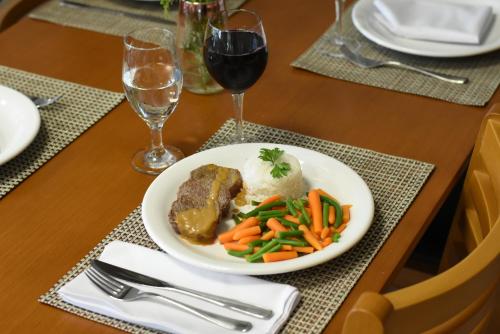 a plate of food with meat and vegetables on a table at Figueiras Hotel & Eventos in São Miguel dʼOeste