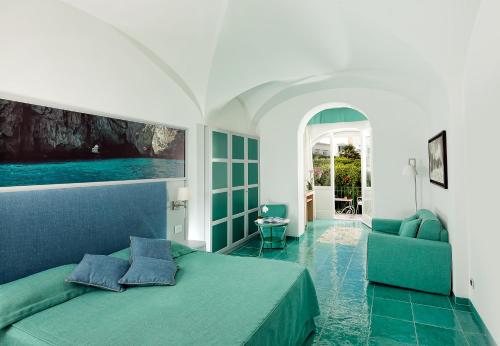 sypialnia z zielonym łóżkiem i kanapą w obiekcie Albergo Gatto Bianco w mieście Capri