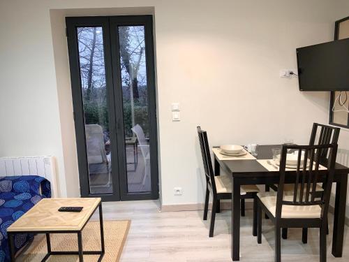 a dining room with a table and chairs and a television at Jouy La longère, proche Hec, Versailles, parking privé gratuit in Jouy-en-Josas