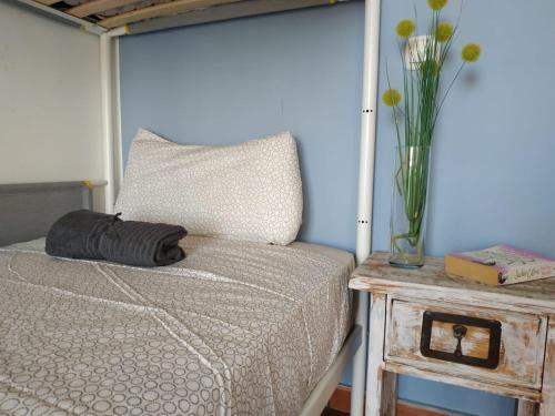 una cama con un jarrón de flores sobre una mesa en Aloha Surf House, en Corralejo