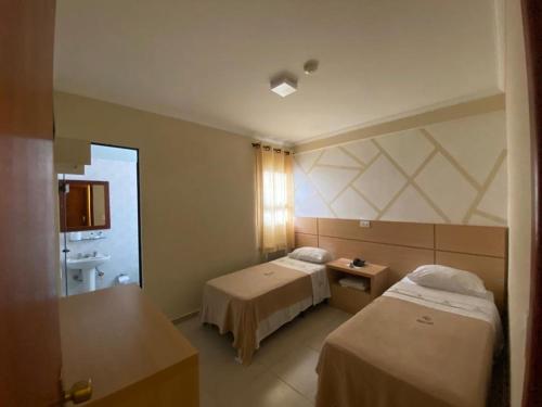 a hotel room with two beds and a bathroom at Hotel Makuxis - Brigadeiro in Sao Paulo