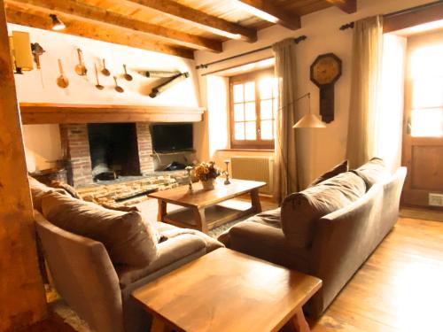 ein Wohnzimmer mit Sofas, einem Tisch und einem Kamin in der Unterkunft Pleta Ordino 18, Duplex rustico con chimenea, Ordino, zona vallnord in Ordino