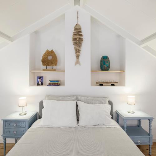 a bedroom with a bed with two tables and two lamps at Fisherman's Inn Loft in Montijo
