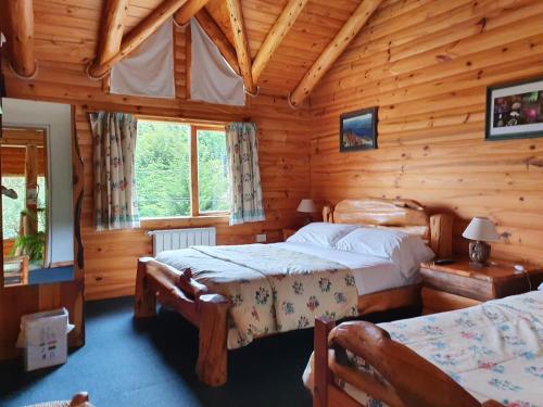 a bedroom with two beds in a log cabin at Hosteria Epulen in Villa La Angostura