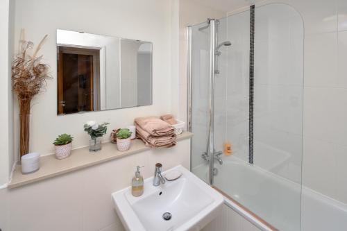 ein weißes Badezimmer mit Waschbecken und Dusche in der Unterkunft The Hub - Spacious, bright and modern with free parking in Milton Keynes