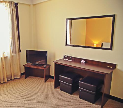 a hotel room with a desk and a mirror at Cazare Karmina in Baia Mare