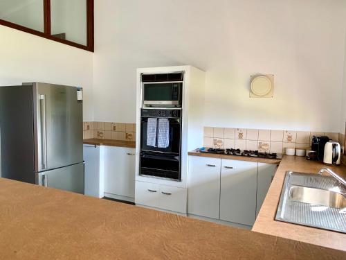 una cocina con armarios blancos y electrodomésticos de acero inoxidable en Beachside House, en Kingscote