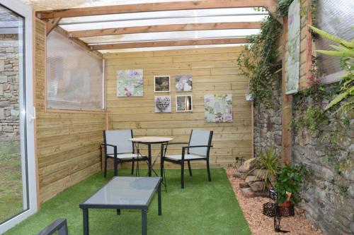 un patio avec une table et des chaises et un mur en pierre dans l'établissement Gîte 3 personnes, possibilité table d'hôtes le soir, à Tréduder