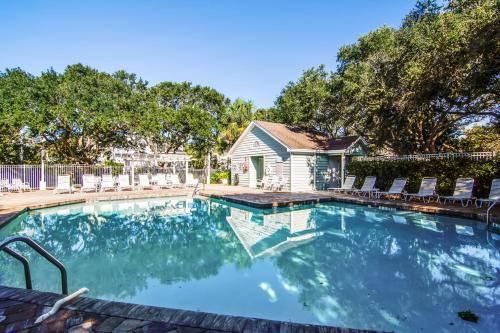 een zwembad met stoelen en een huis bij Pelican Bay 42 in Isle of Palms