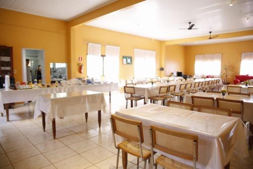 a restaurant with tables and chairs and white tables at Pousada Meribá in Chapada dos Guimarães