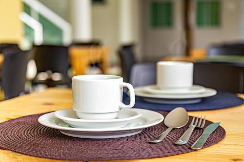 two white cups and saucers on a wooden table at Pousada Maresia Unique Beira Mar in Porto De Galinhas