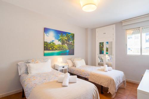 マラガにあるVirginia Beach & private terrace by ELE Apartmentsのベッドルーム1室(ベッド2台付)が備わります。壁には絵画が飾られています。