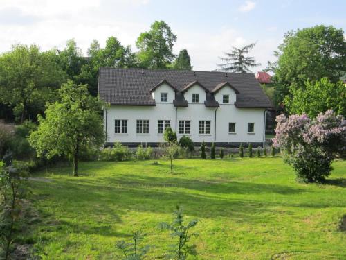 a white house on a green field with trees at Jagnienawinie in Międzybrodzie Żywieckie