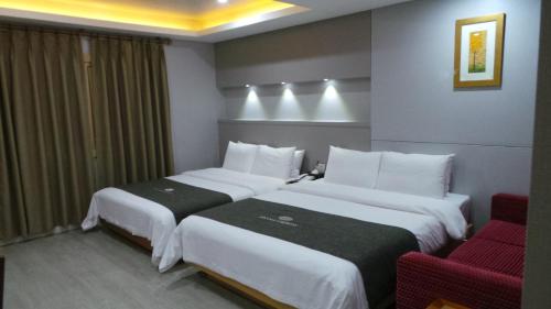 a hotel room with two beds and a red chair at Amour Hotel in Suwon