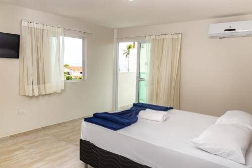 1 dormitorio con 1 cama blanca grande y ventana en Pousada Maresia Unique Beira Mar, en Porto de Galinhas