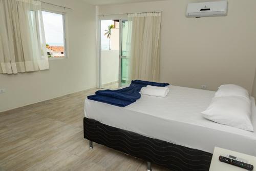 a bedroom with a white bed with blue towels on it at Pousada Maresia Unique Beira Mar in Porto De Galinhas