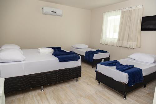 a room with three beds and a window at Pousada Maresia Unique Beira Mar in Porto De Galinhas