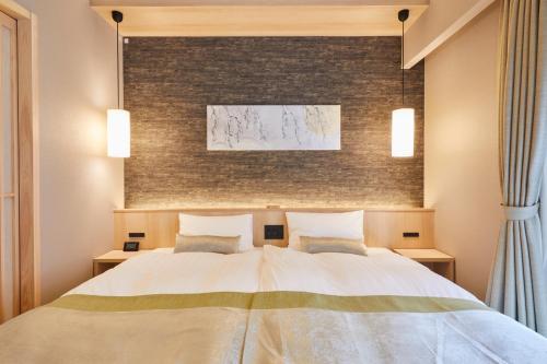 a bedroom with a large white bed with two pillows at Rinn Shirakawa South in Kyoto