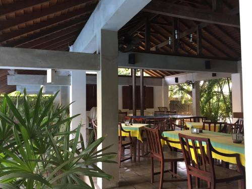 a restaurant with yellow tables and chairs and some plants at Hotel Sunflower in Kataragama
