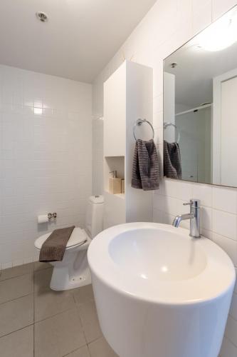 a white bathroom with a sink and a toilet at S&P Apartments - Tank St in Brisbane