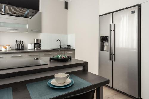 een keuken met een koelkast en een tafel met een kopje bij Apartament w centrum in Gdynia