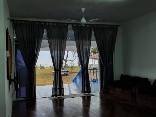 a living room with a window with a view of a yard at ALA Beach Lodge - Ketapang Homestay in Kota Bharu