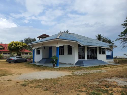 a small white house with a blue roof at ALA Beach Lodge - Ketapang Homestay in Kota Bharu