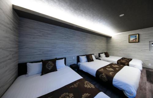 a room with two beds and a wall at GRAND BASE Takamatsu in Takamatsu