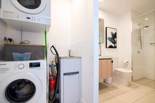 a bathroom with a washing machine and a toilet at Hope Street Apartments by CLLIX in Brisbane