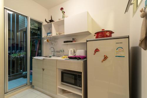 a kitchen with a refrigerator and a microwave at Baan Kiang Fah Hua Hin 23-386 in Hua Hin