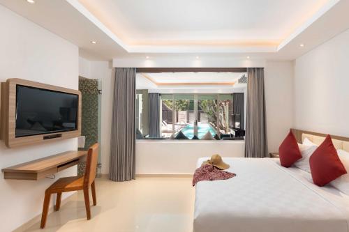 a bedroom with a bed and a television and a desk at Downtown Villas in Seminyak