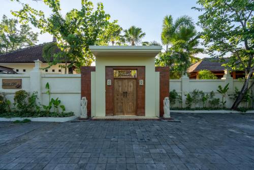 a house with a wooden door in a driveway at Benian Villas in Nusa Dua