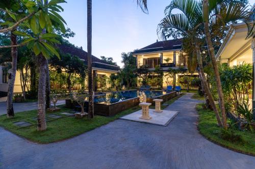 a resort with a swimming pool and palm trees at Benian Villas in Nusa Dua