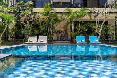 a swimming pool with two lounge chairs and a building at Benian Villas in Nusa Dua