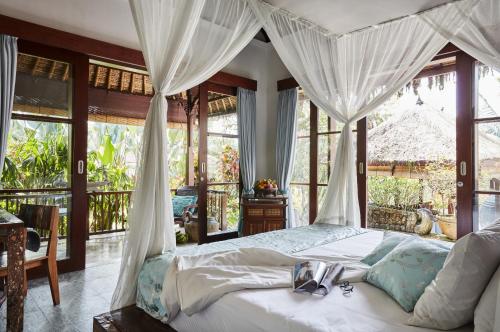 a bedroom with a bed with white drapes at Villa Bayad in Payangan