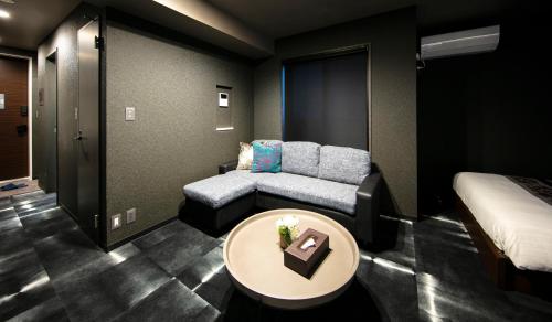 a room with a couch and a bed and a table at GRAND BASE Takamatsu in Takamatsu