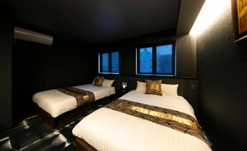 two beds in a room with black walls and windows at GRAND BASE Takamatsu in Takamatsu