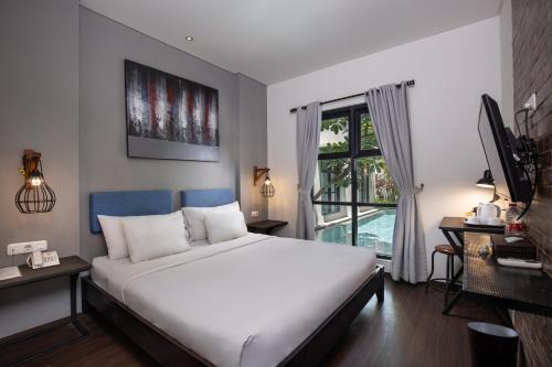 a bedroom with a large white bed and a window at The Aswana Seminyak in Seminyak