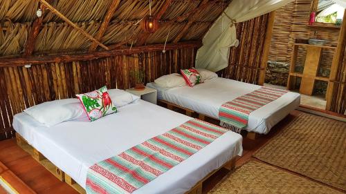 une chambre avec deux lits dans une cabane dans l'établissement El Búho Bacalar Eco-Cabañas Hostal, à Bacalar