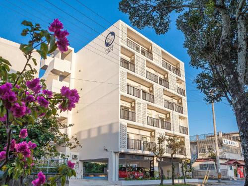 a white building with purple flowers in front of it at Kariyushi Condominium Resort Miyakojima Fukugi Stays in Miyako-jima