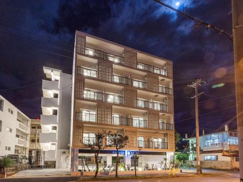 a tall white building with people in front of it at Kariyushi Condominium Resort Miyakojima Fukugi Stays in Miyako-jima