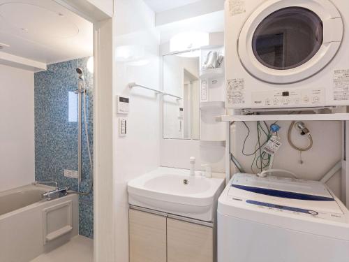 a white bathroom with a sink and a washing machine at Kariyushi Condominium Resort Miyakojima Fukugi Stays in Miyako Island