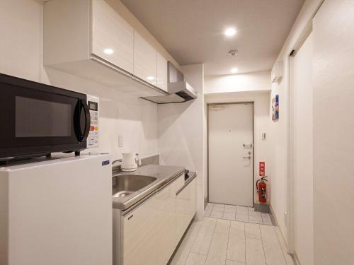a small kitchen with a sink and a microwave at Kariyushi Condominium Resort Miyakojima Fukugi Stays in Miyako-jima