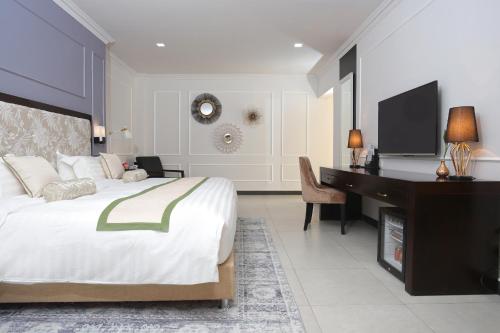 a bedroom with a bed and a desk and a piano at Queenco Hotel & Casino in Sihanoukville